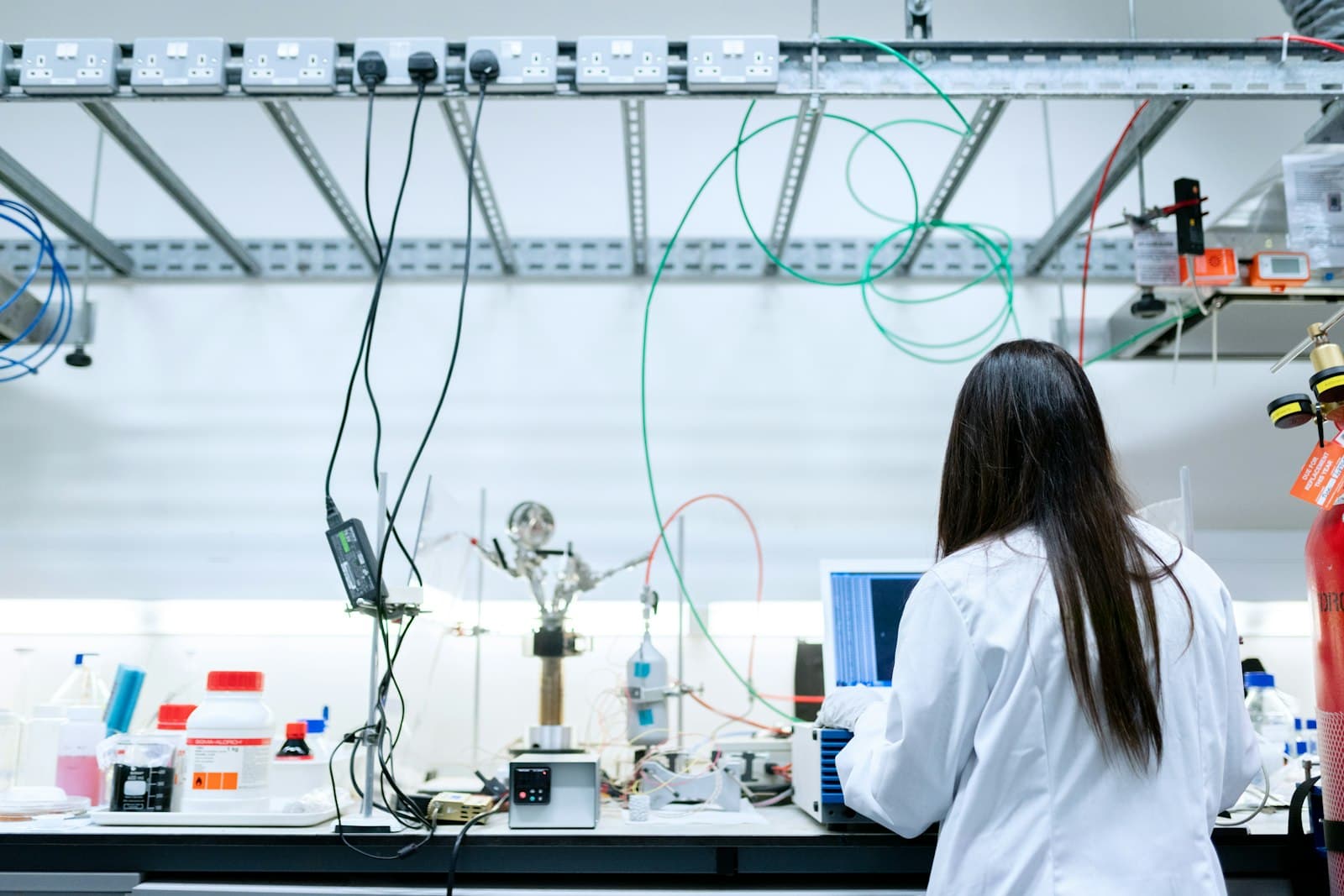 A scientist in a white lab coat using a laptop in a laboratory — Photo by ThisisEngineering on Unsplash