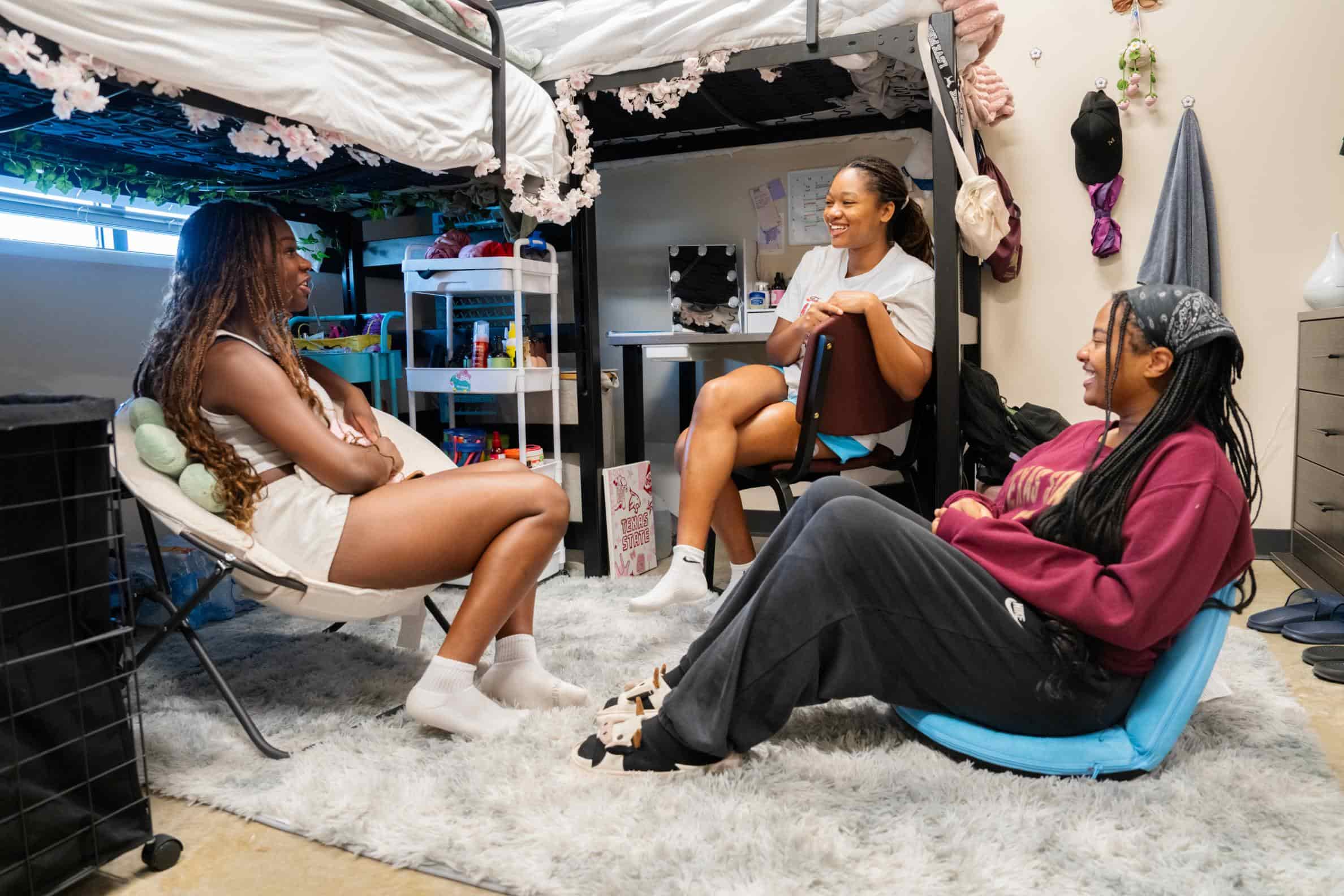 Three students talking in a Texas State residence hall room
