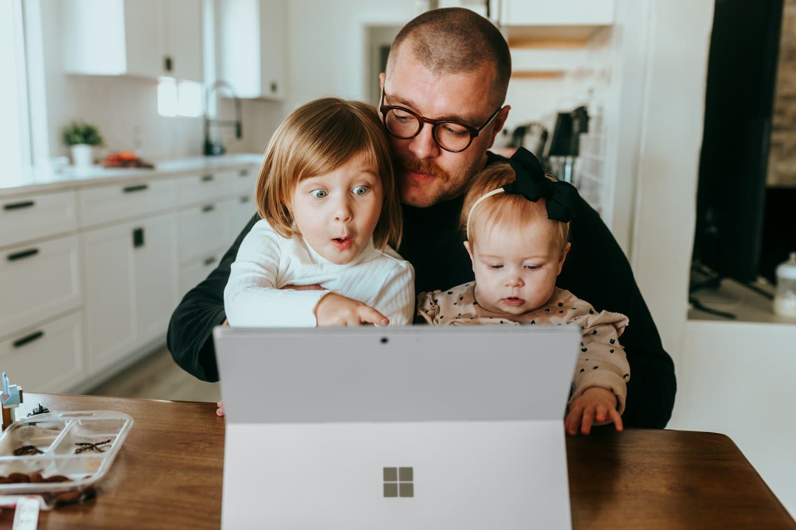 a man and two children looking at a laptop — Photo by Surface on Unsplash