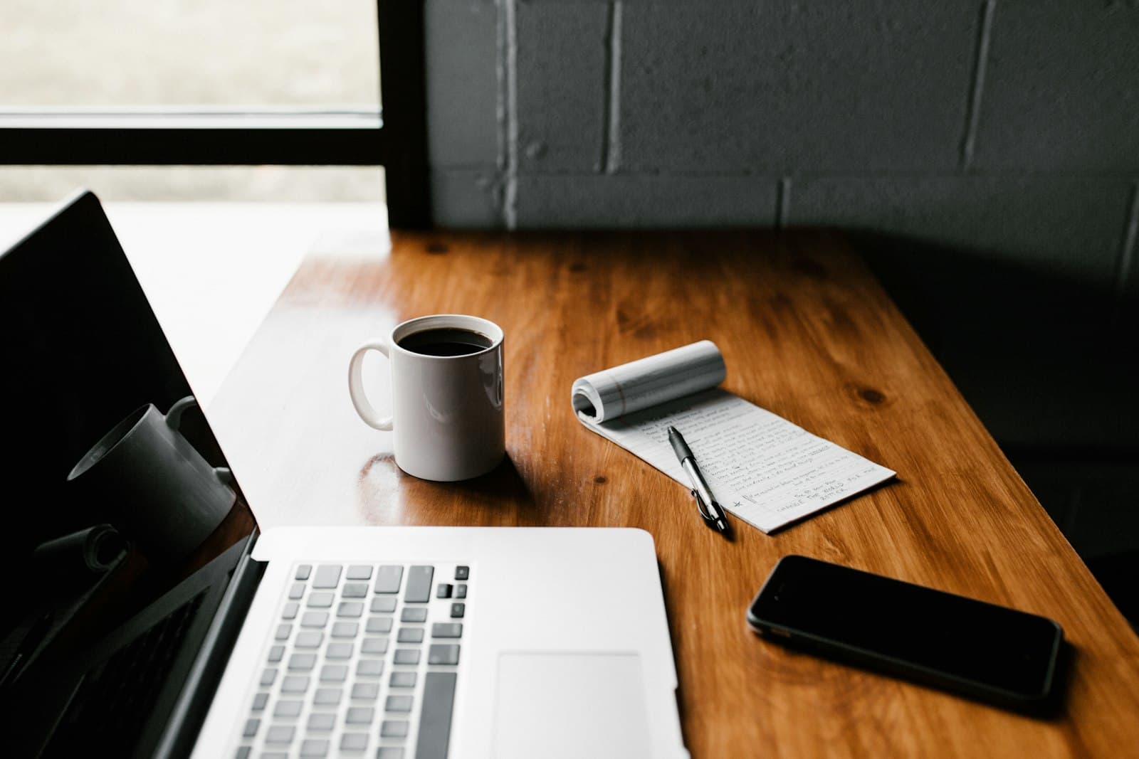MacBook Pro, white ceramic mug,and black smartphone on table — Photo by Andrew Neel on Unsplash